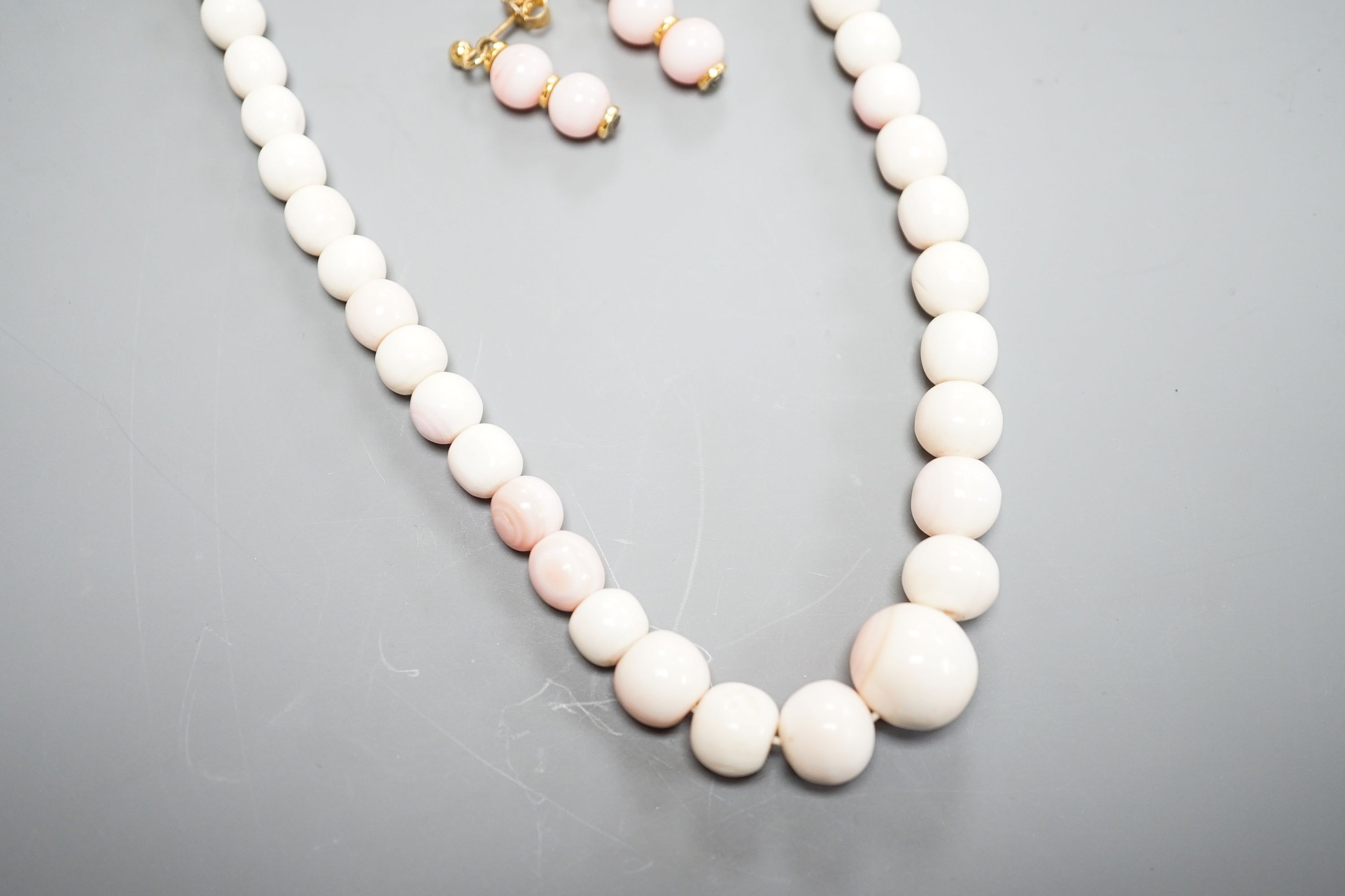 A single strand graduated bleached coral bead necklace, 51cm, gross 43.5 grams and a pair of 750 yellow metal and bleached coral earrings, 24mm, gross 4 grams.